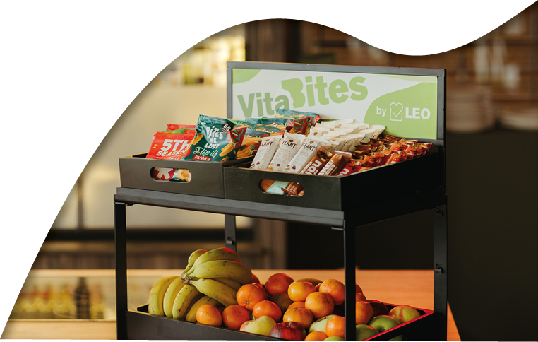 A black tray with a sign that says “Vitaites" on it. The tray is filled with various fruits and snacks. AI generated content