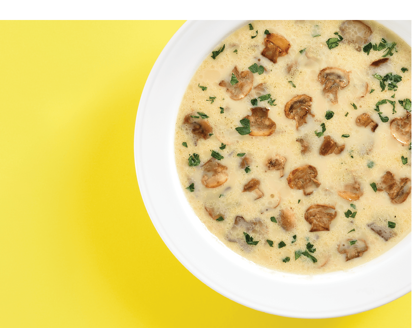 Close up view of creamy mushroom soup over yellow background with free text space. Top view, flat lay