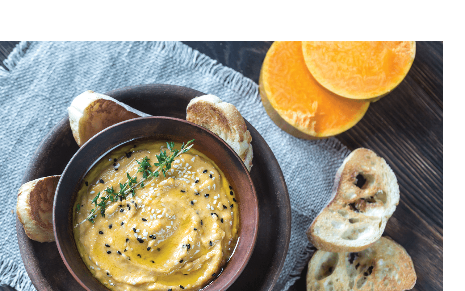 Bowl of pumpkin hummus with slices of toasted bread