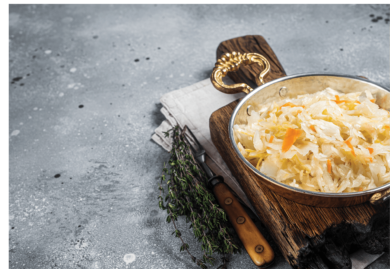 Homemade sauerkraut with black pepper and salt in a skillet. Gray background. Top view. Copy space.