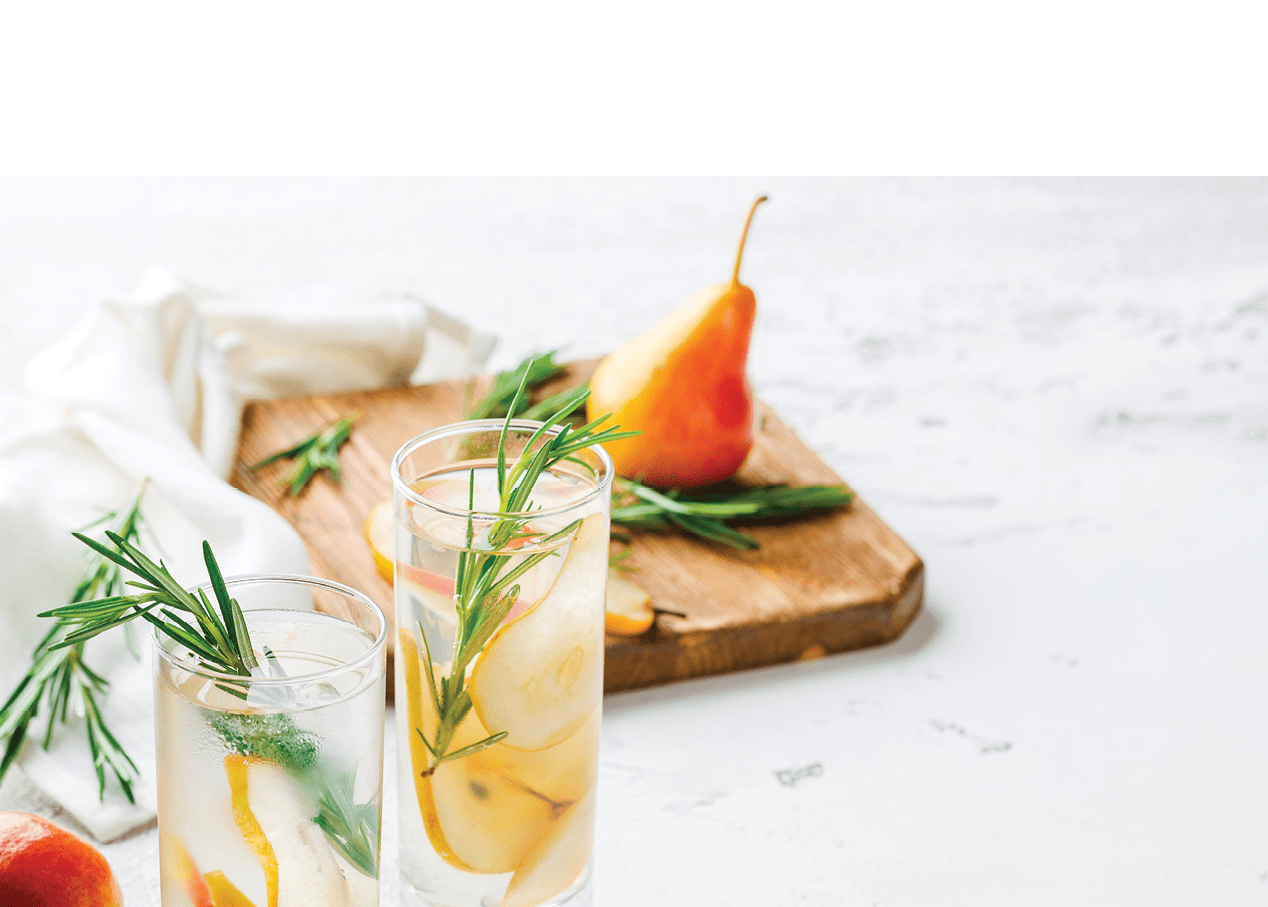 Summer drinks, rosemary pear cocktails with ice in glasses. Refreshing summer homemade Alcoholic or non-alcoholic cocktailsor Detox infused flavored water. Space for text.