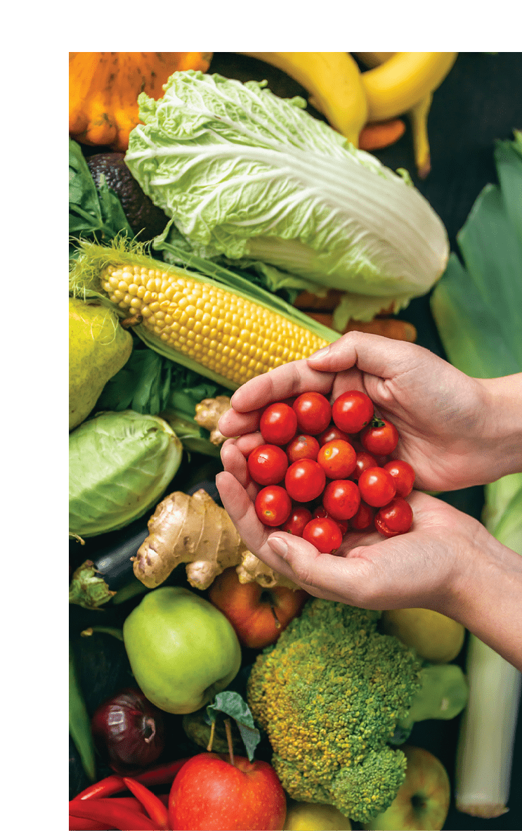 Small cherry tomatoes in women's hands on a blurred background of vegetables on the kitchen table.