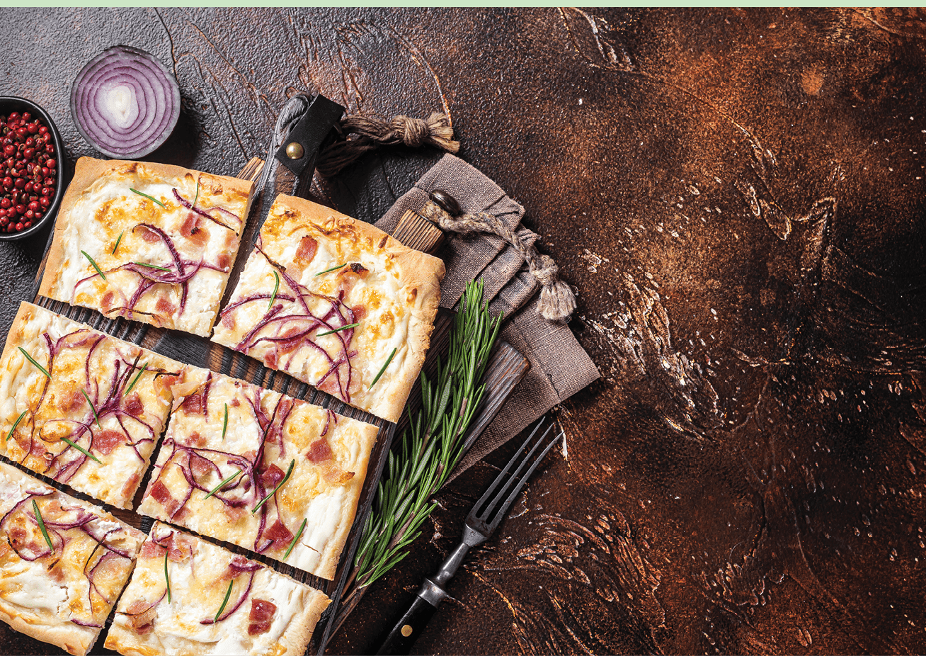 French tarte flambee with cream cheese, bacon and onions. Flammkuchen from Alsace region. Dark background. Top view. Copy space.