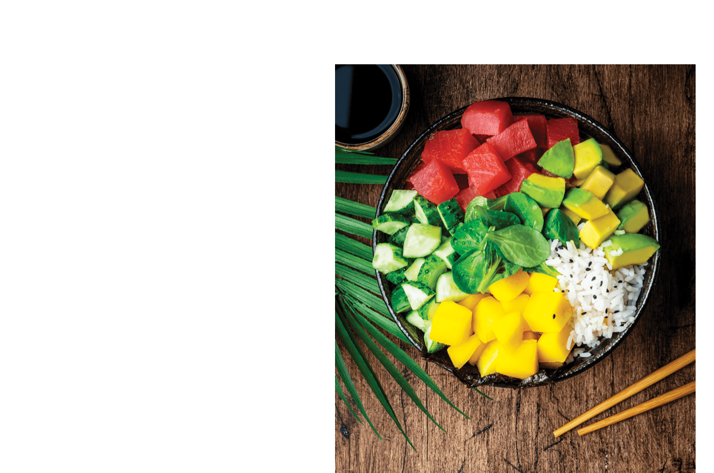 Poke bowl with fresh tuna, avocado, mango, cucumber, lettuce and white rice. Soy sauce, lime and sesame dressing. Old rustic wooden table background, top view
