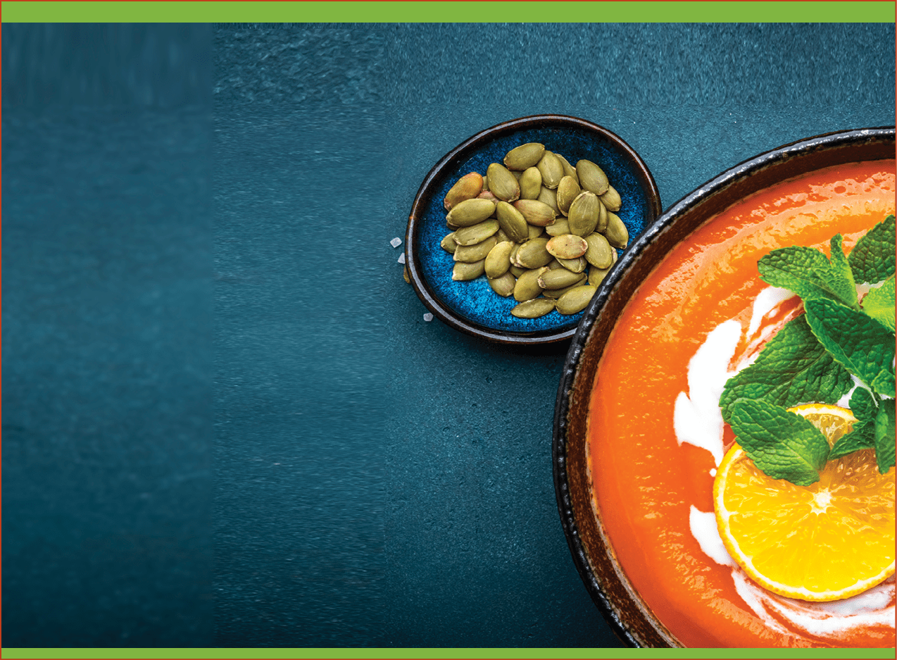 Sweet autumn pumpkin soup with cream, tangerine and mint. Winter healthy vegetarian comfort slow food. Soup bowl on green table background. Top view