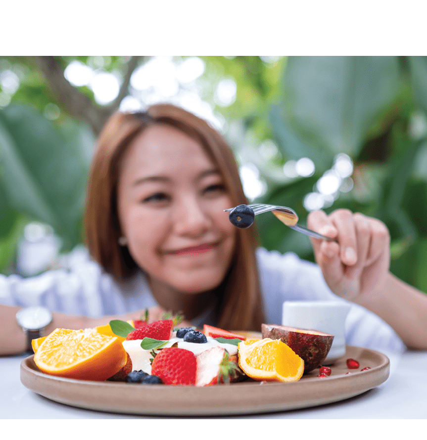 A young woman eating mixed fruits french toast brunch in restaurant
