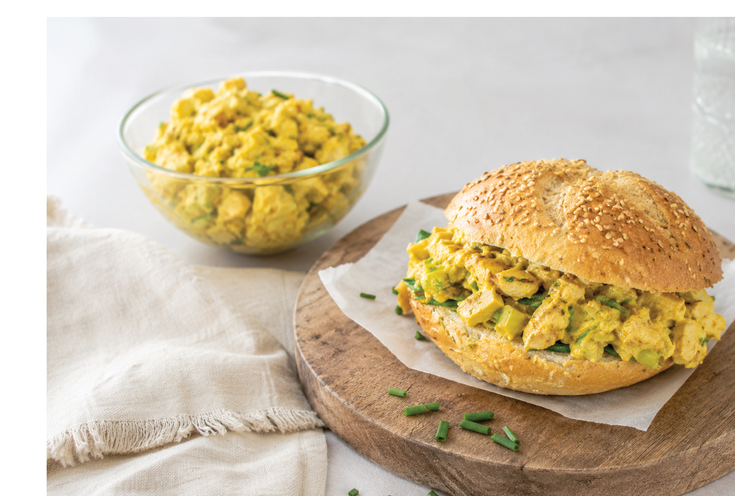 A sandwich on a wooden board with a bowl of rice on the side. Description generated by AI