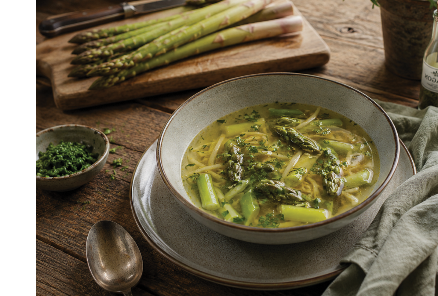 A bowl of soup with broccoli and a spoon on a table. Description generated by AI
