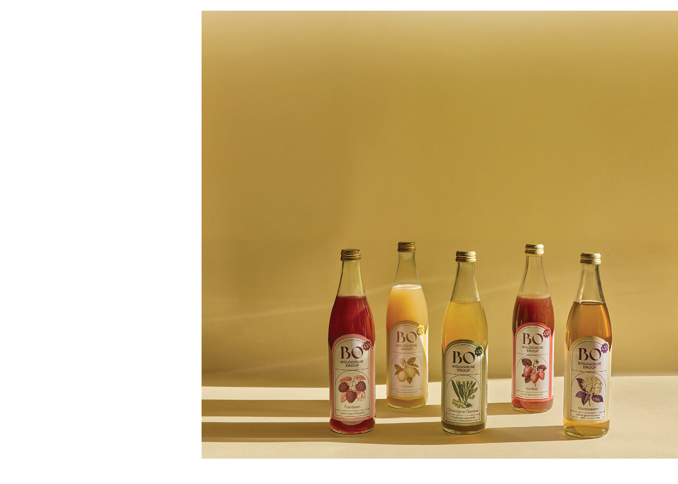 Four bottles of juice are lined up on a table. Description generated by AI