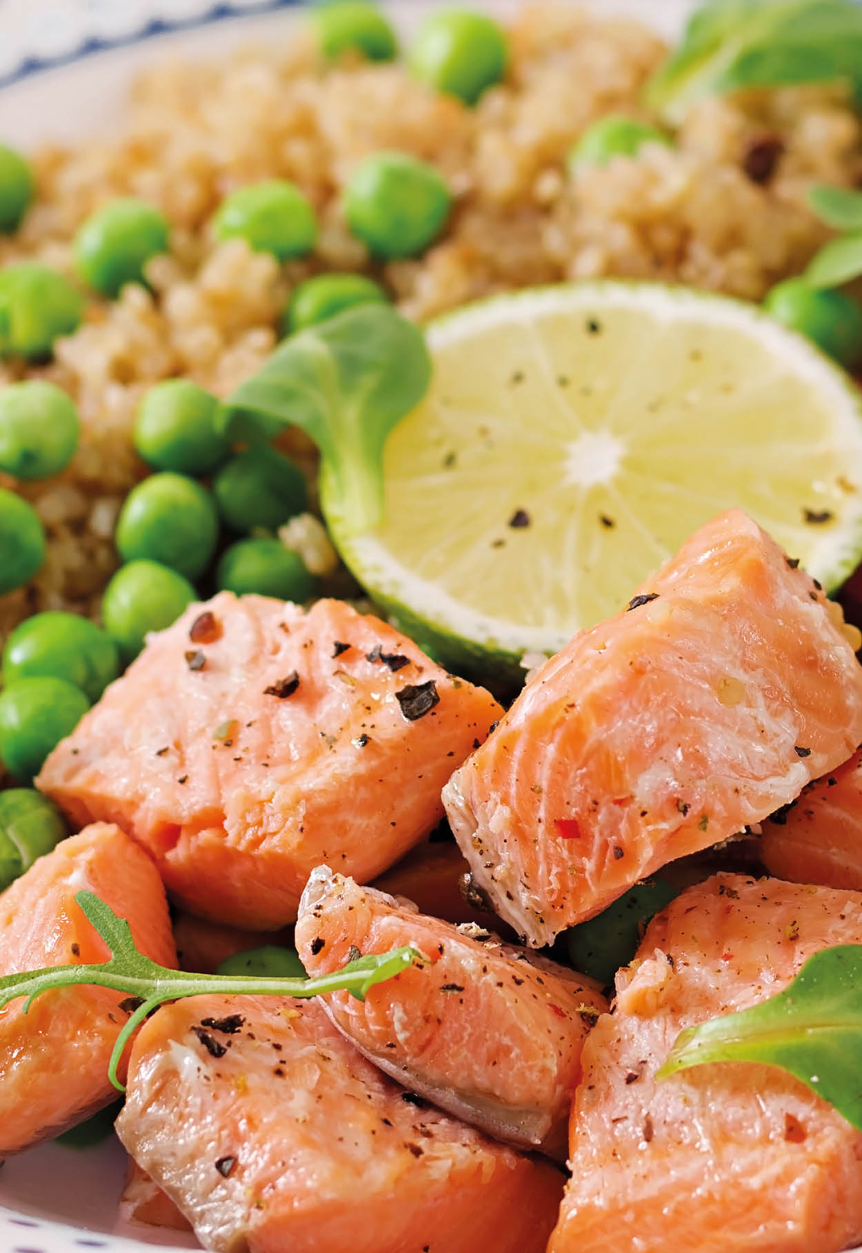 Healthy dinner. Slices of grilled salmon, quinoa, green peas, tomato, lime and lettuce leaves