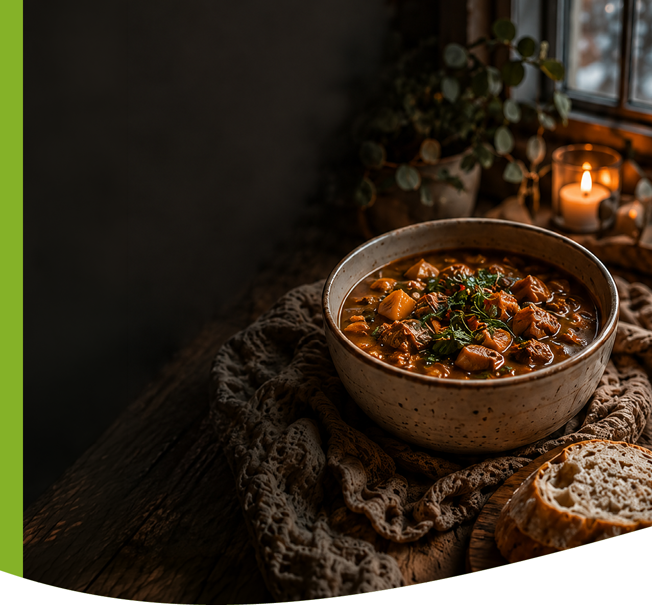 A rustic bowl of hearty stew garnished with herbs sits on a textured cloth next to sliced bread on a wooden table with a lit candle and plant in the background. Description generated by AI