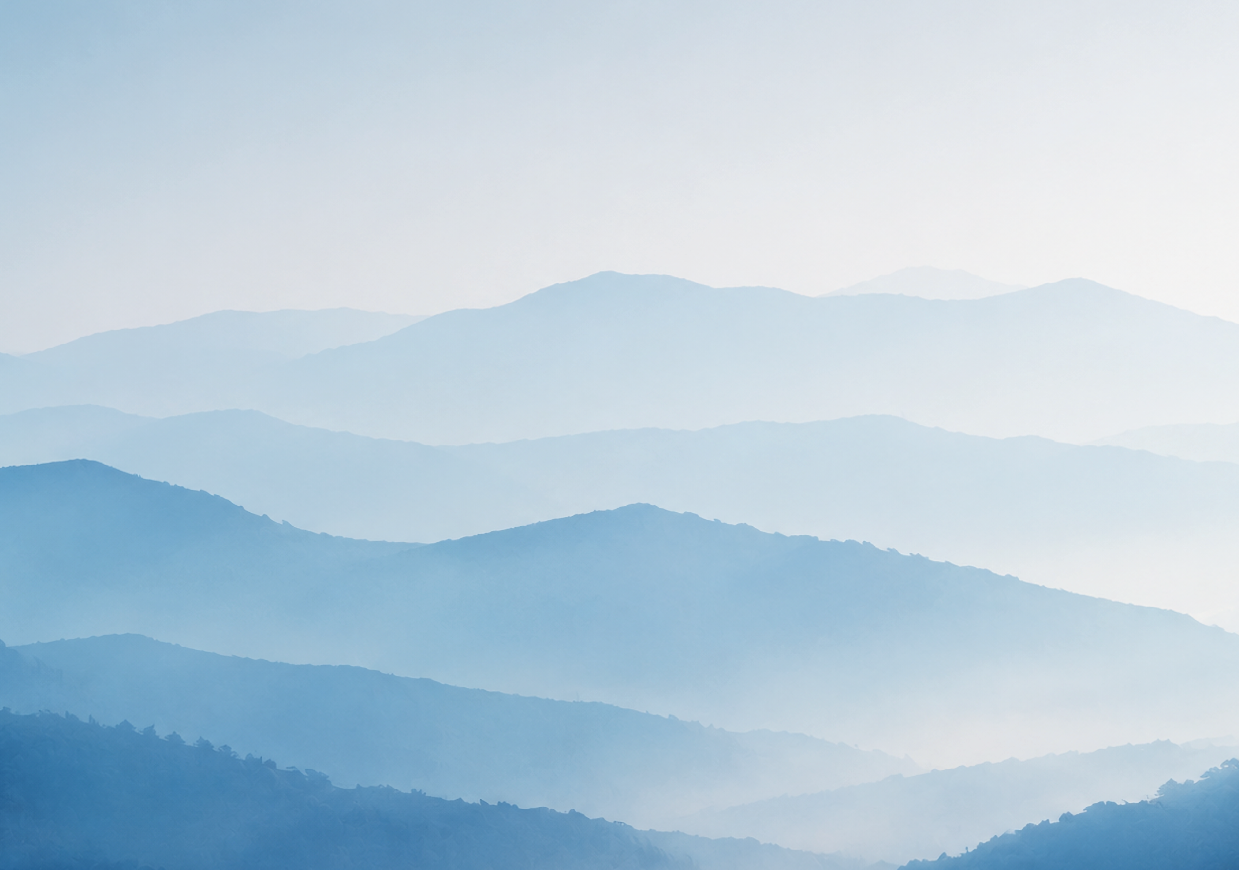 Layers of misty blue mountains fade into the distance under a pale sky. Description generated by AI