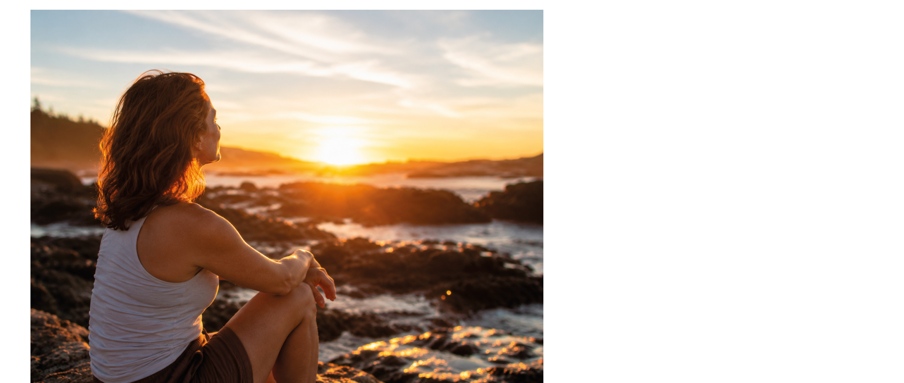 A woman sitting on rocks with her legs crossed. Description generated by AI