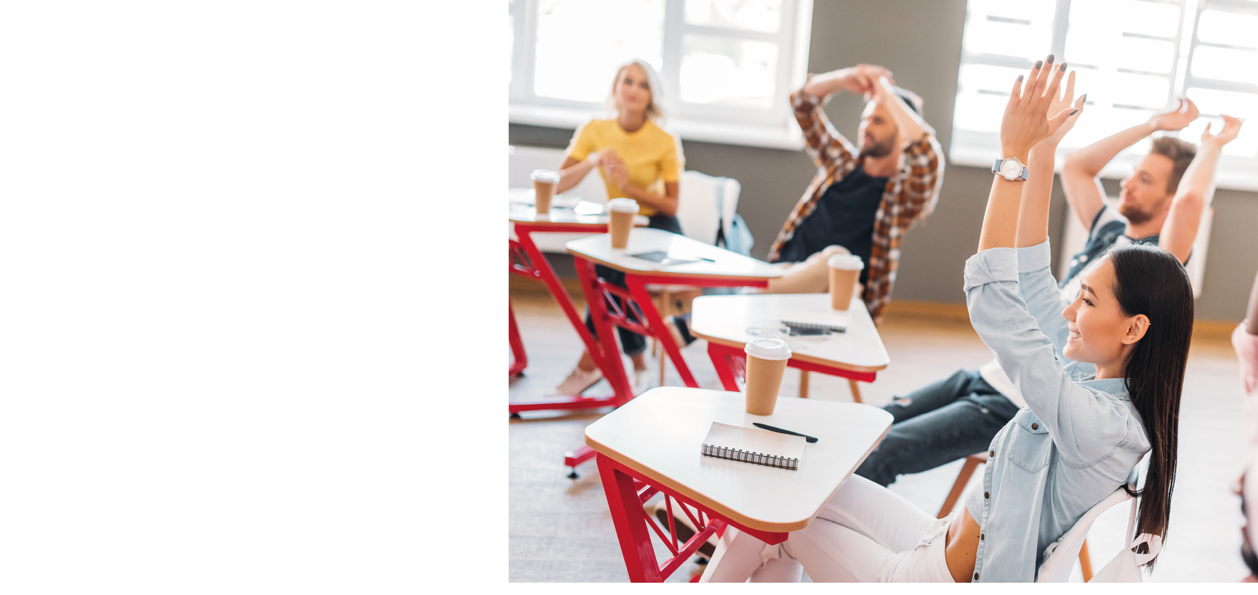 A woman in a blue shirt is sitting at a desk with her hands raised. Description generated by AI