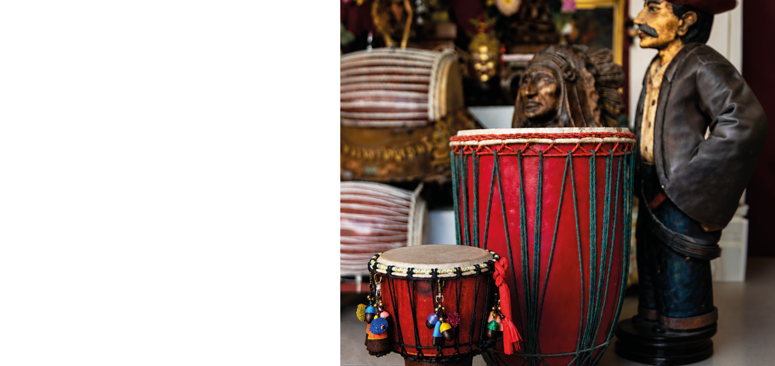 A red drum with a black and red drumstick in front of a statue of a man in a red hat. Description generated by AI