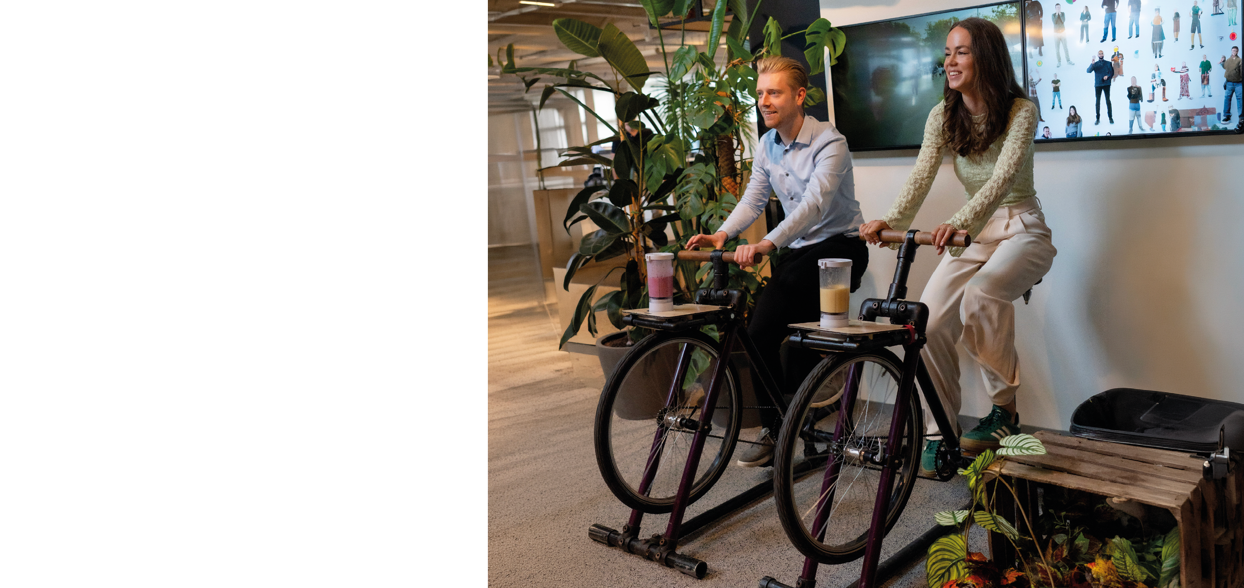 Two people on exercise bikes in front of a large screen. Description generated by AI