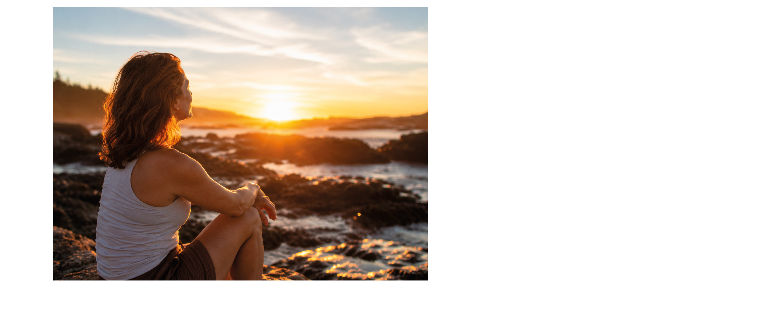 A woman sitting on rocks with her legs crossed. Description generated by AI
