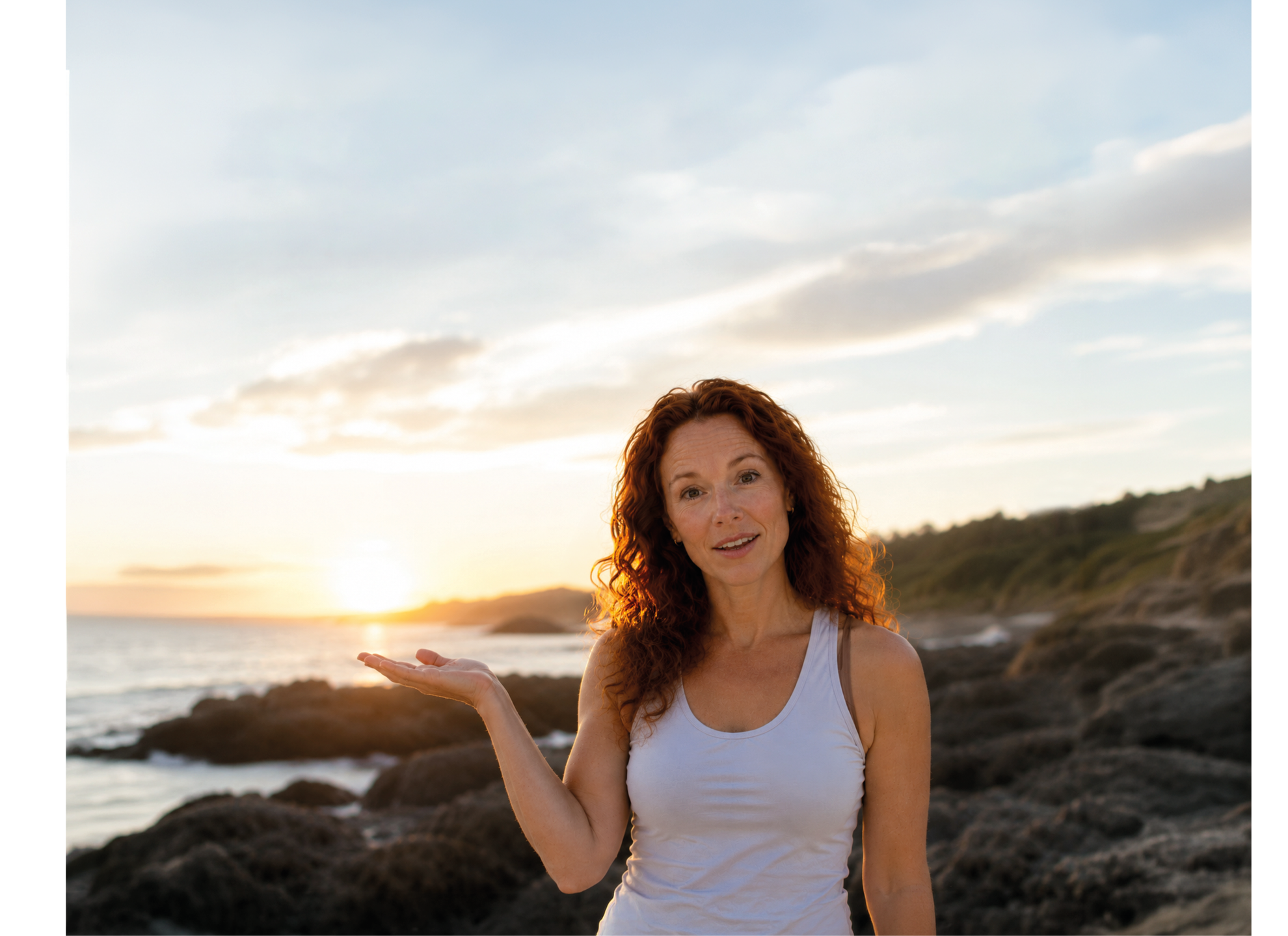 A woman with red hair and a white tank top is standing on a beach. Description generated by AI